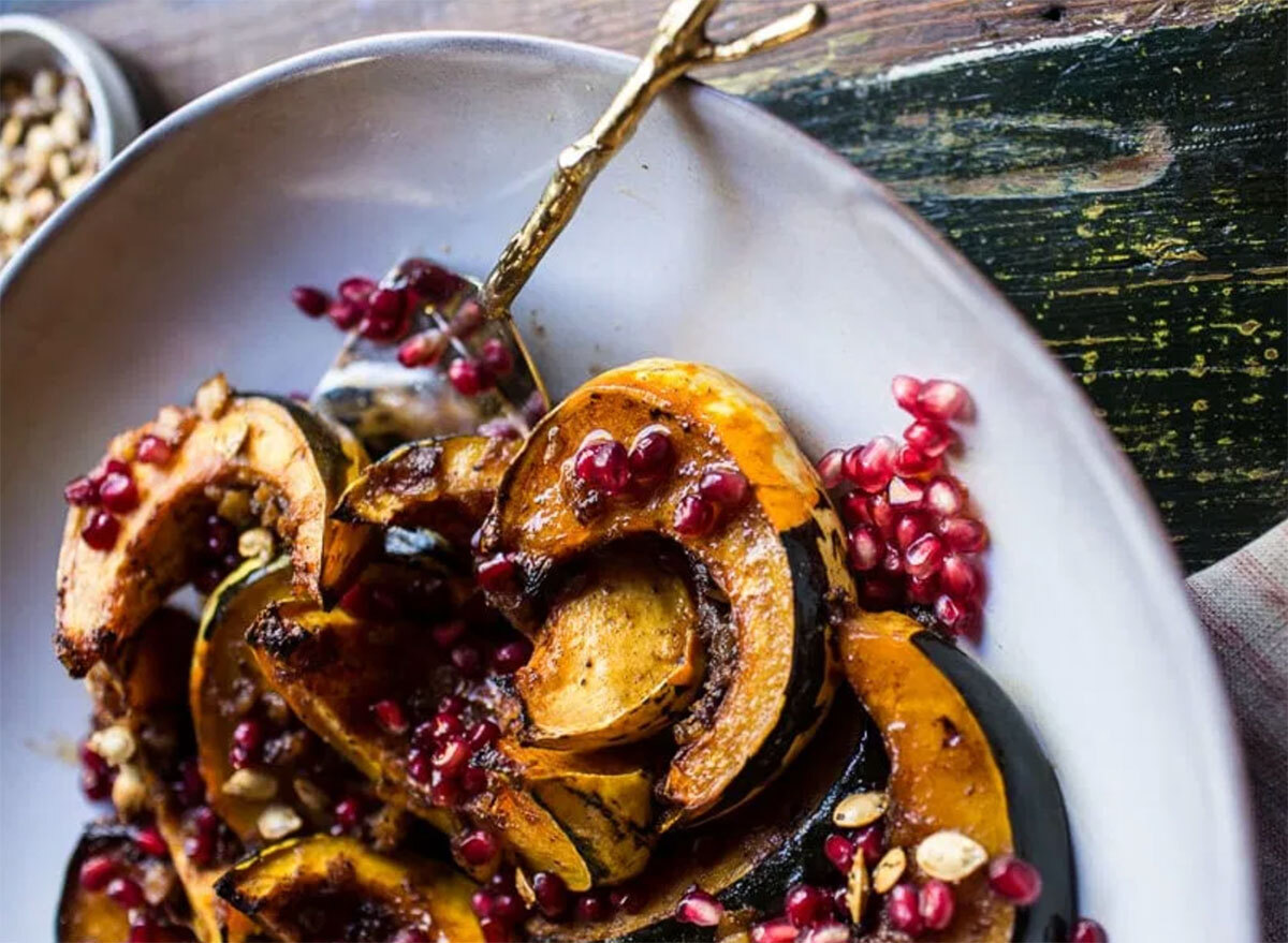 pineapple roasted acorn squash sliced with pomegranate seeds on white plate