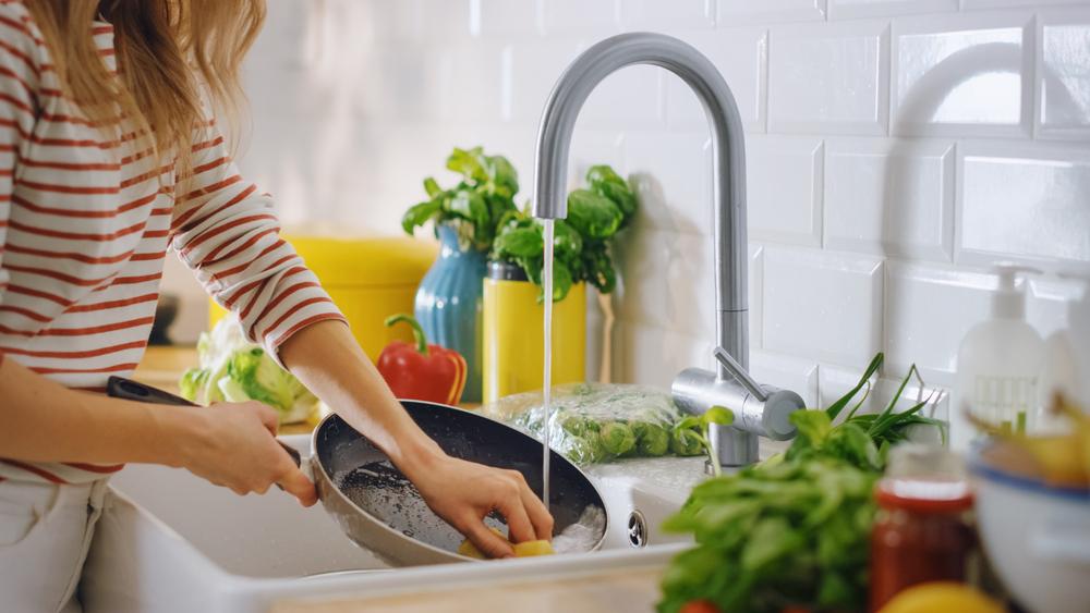 A woman washing dishes in the kitchen sink