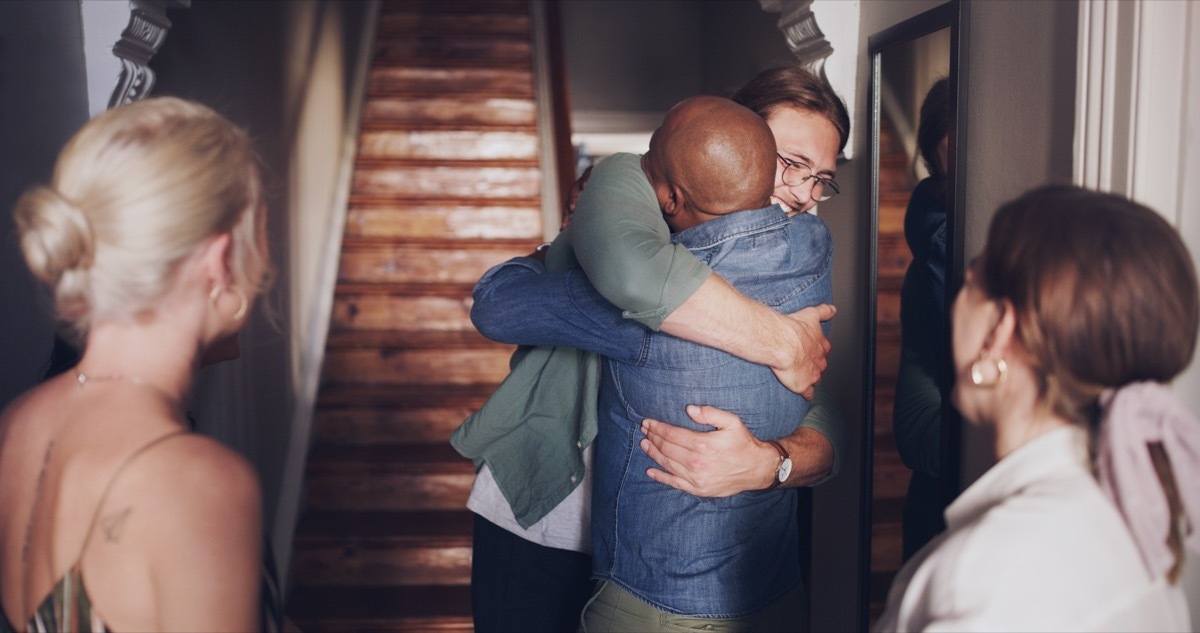 Hug, love and friends meeting at a reunion, home support and social celebration at a housewarming. Diversity welcome, affection greeting and men and women hosting a party to celebrate friendship