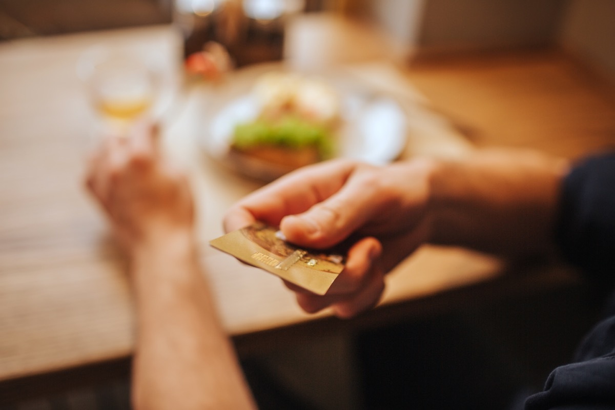 close up of a mail hand hanging server his card to pay the bill at a restaurant