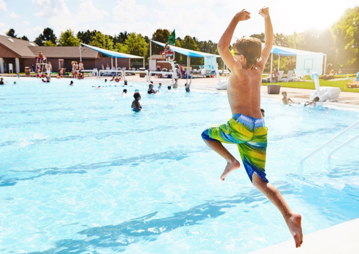 young boy jumping into pool