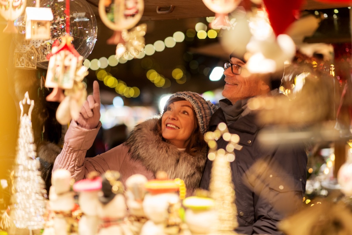 man and woman browsing christmas market souvenir shop on town hall square