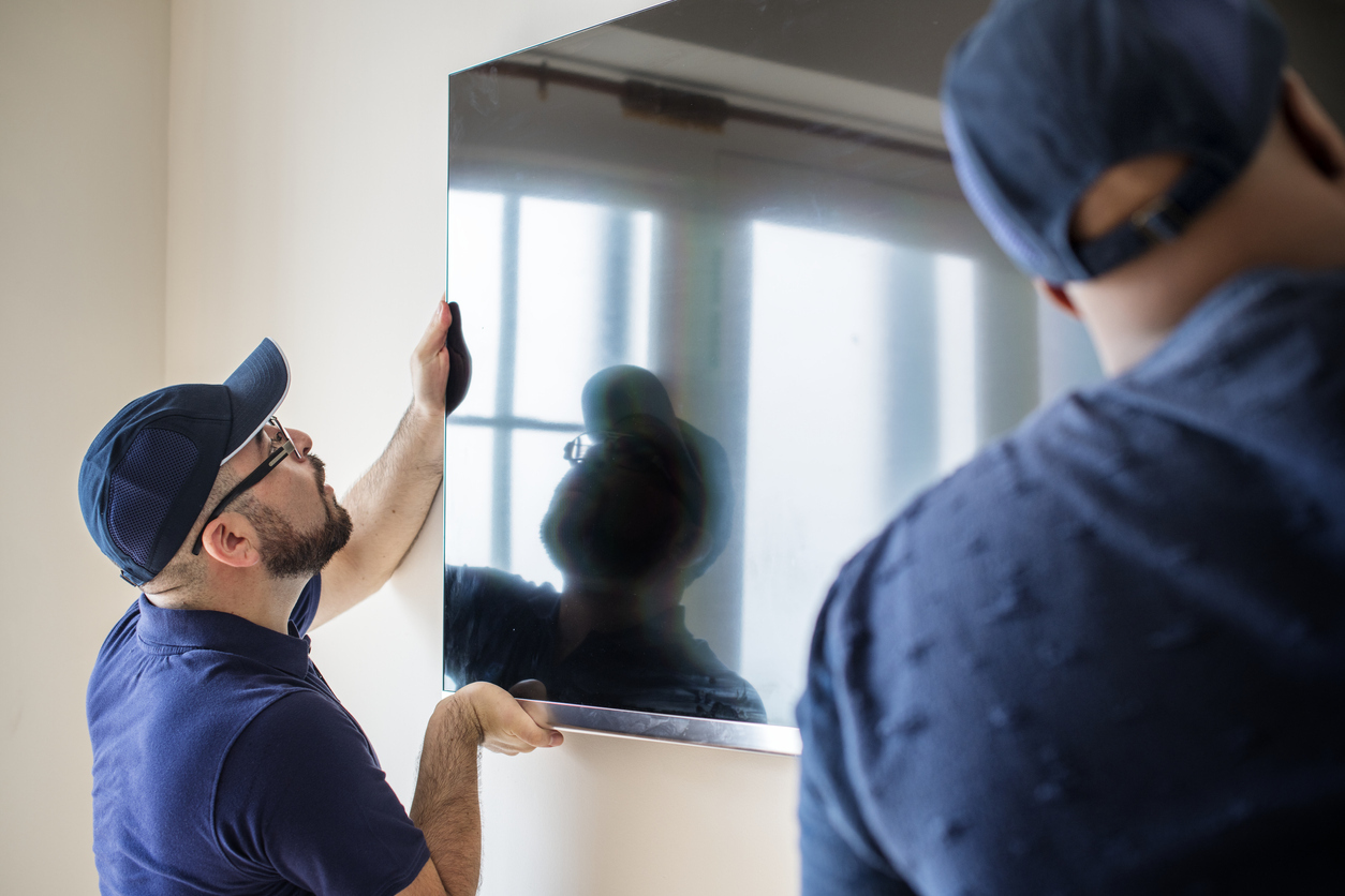 Two delivery people installing a television on the wall