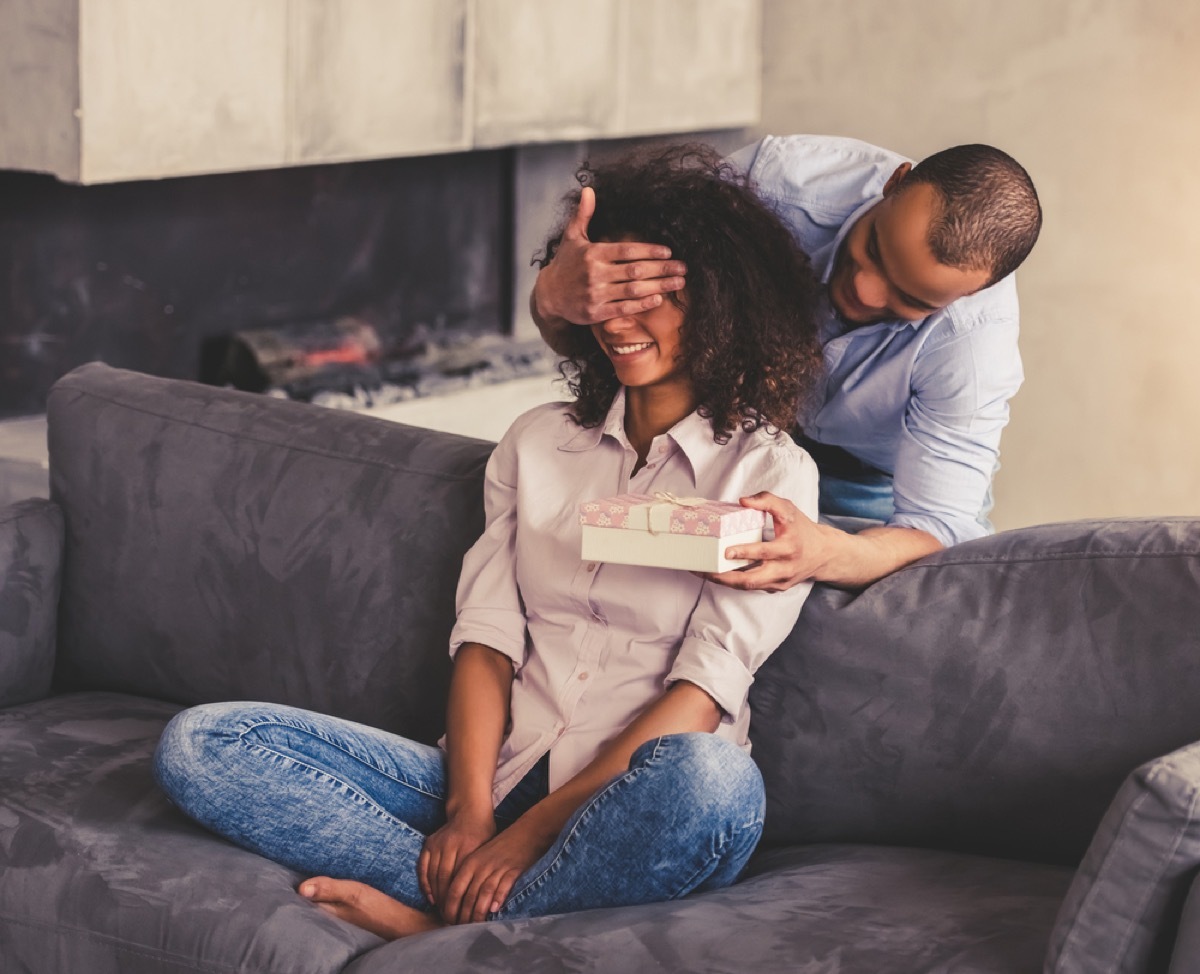 man covering woman's eyes and giving her present, best gifts for girlfriend