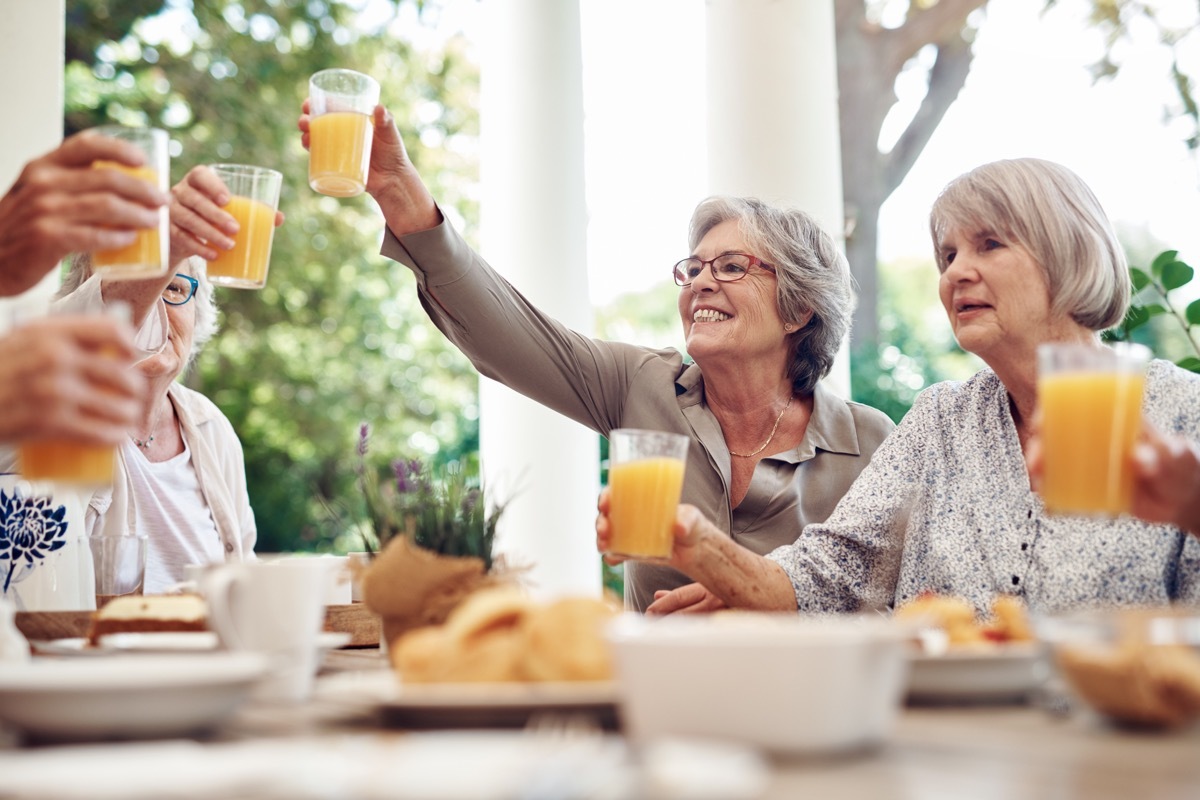 Cropped shot of a group of seniors sitting together and raising their fruit juice glasses for a toast