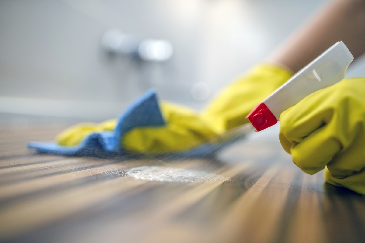 close up of table being cleaned with spray bottle and rag