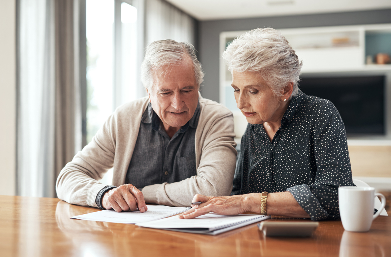 A senior couple sitting at a table looking over documents