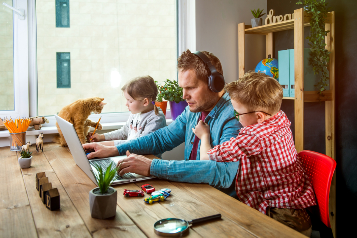 man working at kitchen table while kids and cats bother him