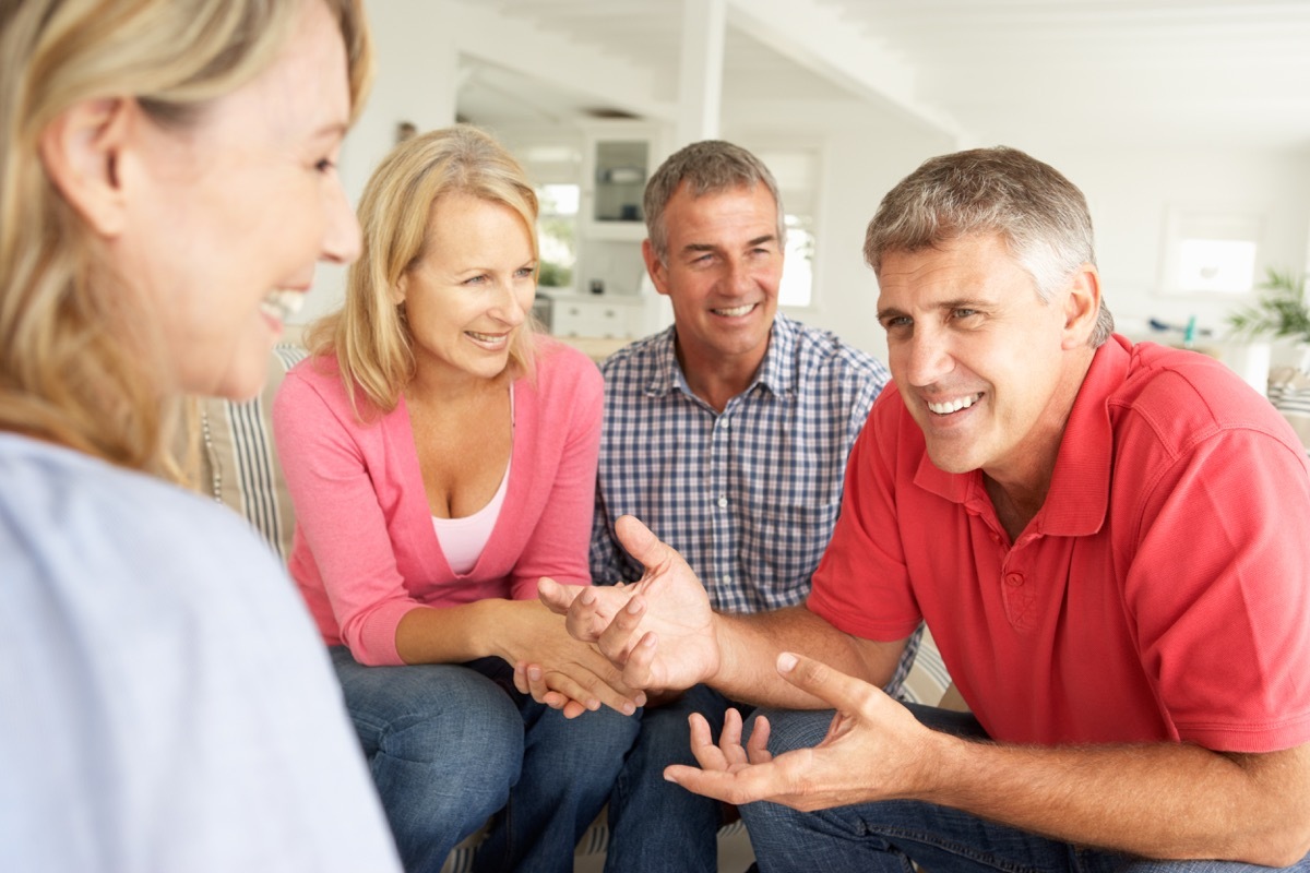 Middle aged friends talking sitting on couch