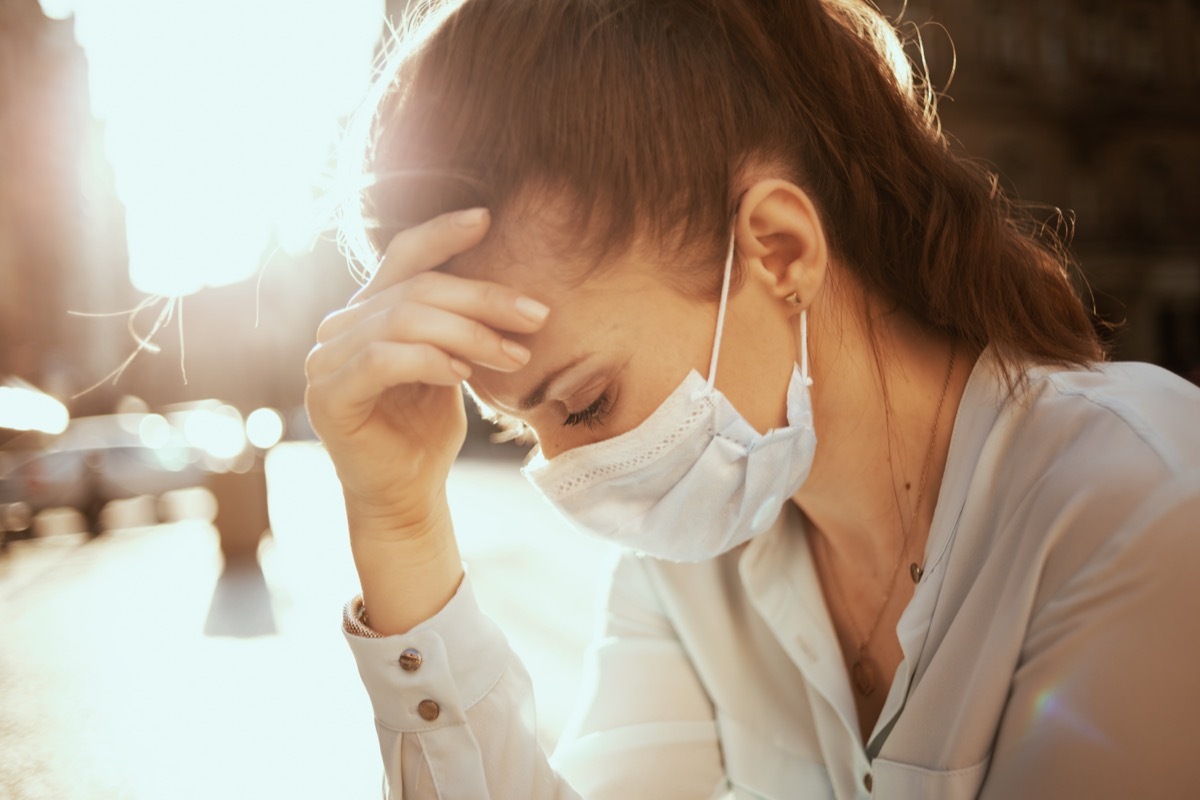 Life during covid-19 pandemic. Portrait of stressed stylish woman in blue blouse with medical mask outdoors on the city street.