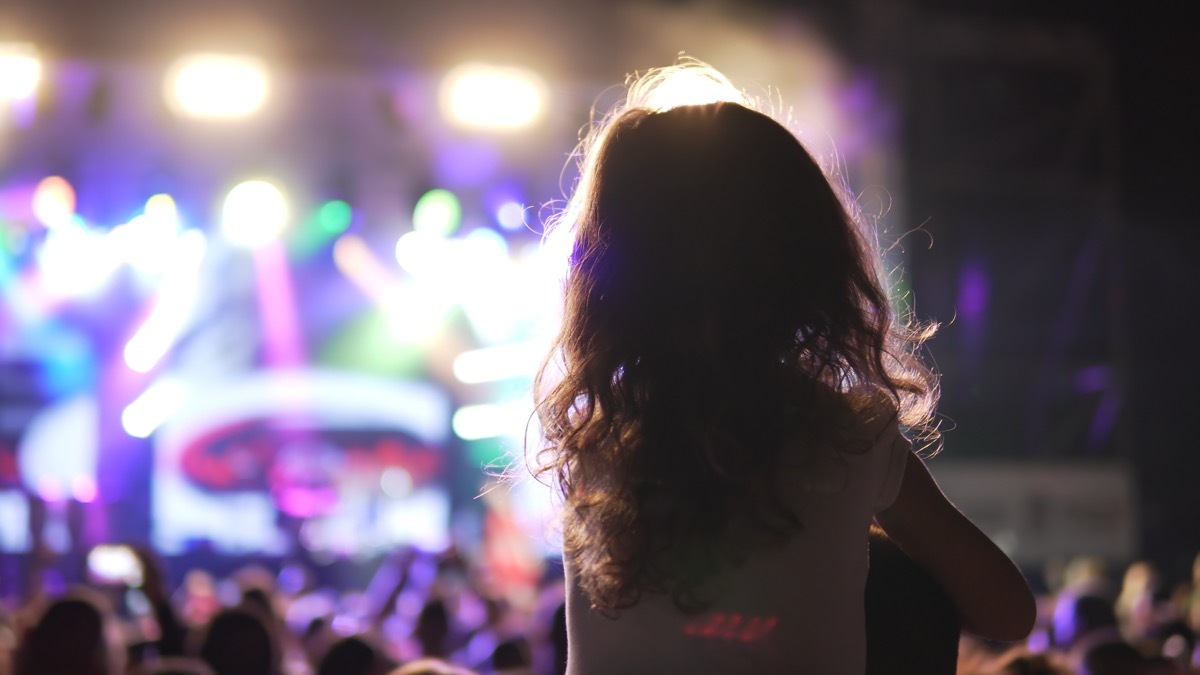 Little girl on shoulders watching a concert