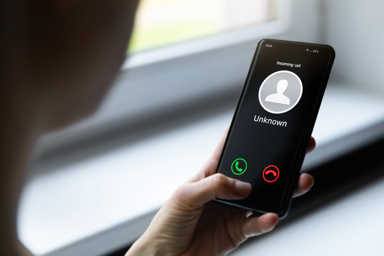 A woman receiving a phone call on her smartphone from an unknown caller, likely to be a robocall