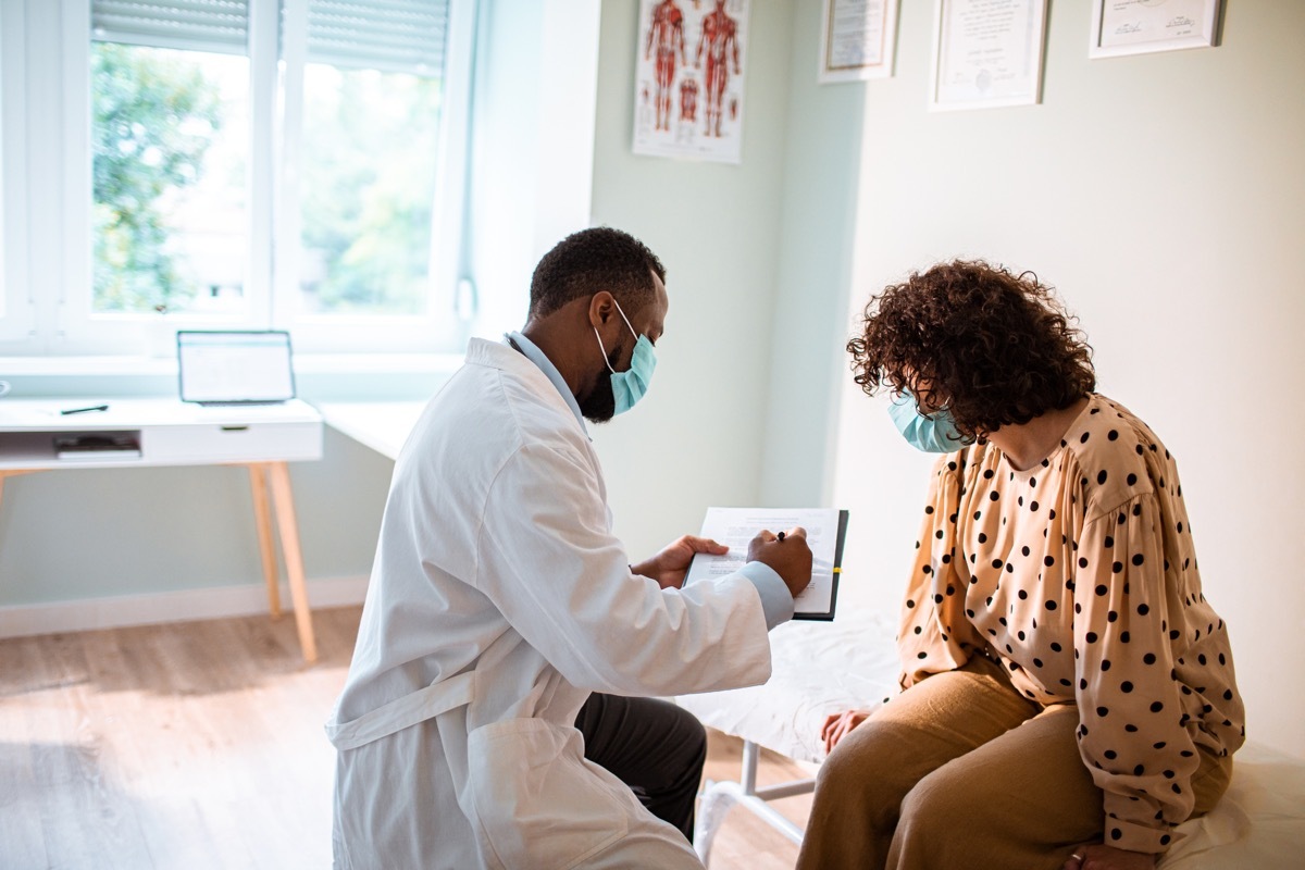 woman gets a medical exam, wearing a mask