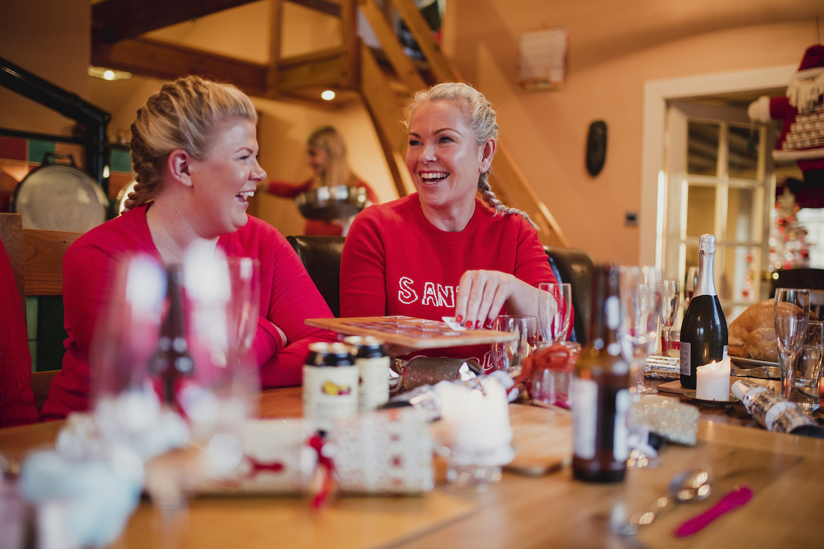 Mature woman and her daughter are enjoying a mini game of cards at the dining table on christmas