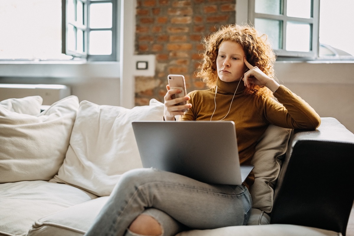 woman sitting on sofa and using portable devices, having video call from family