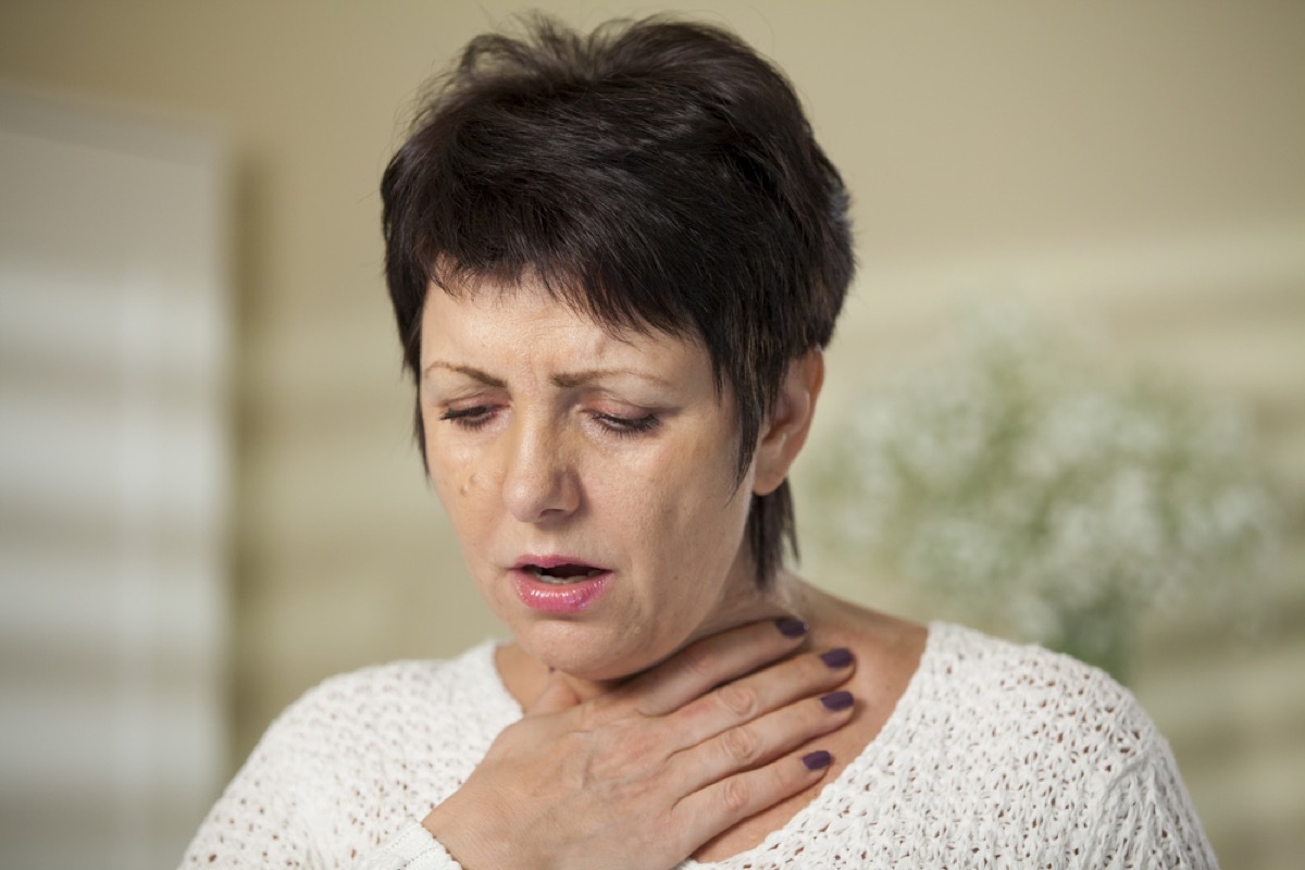 older woman clutching throat, signs your cold is serious