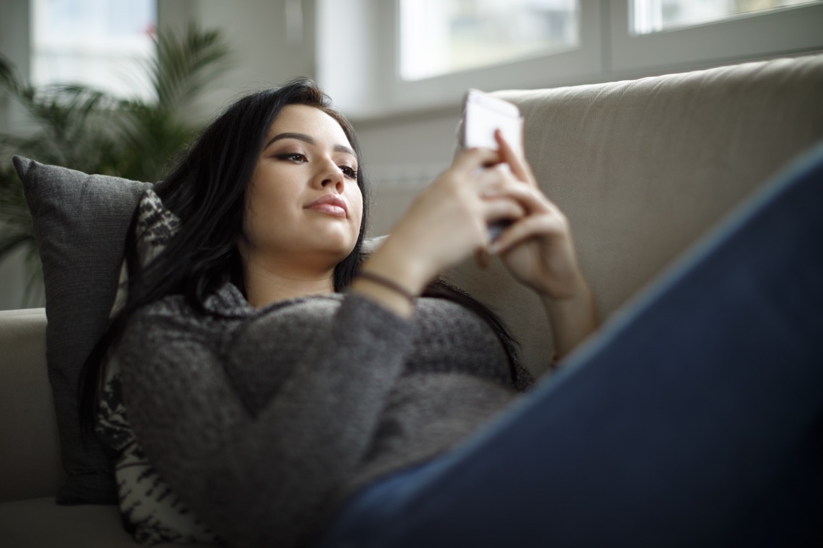 young asian woman texting on couch