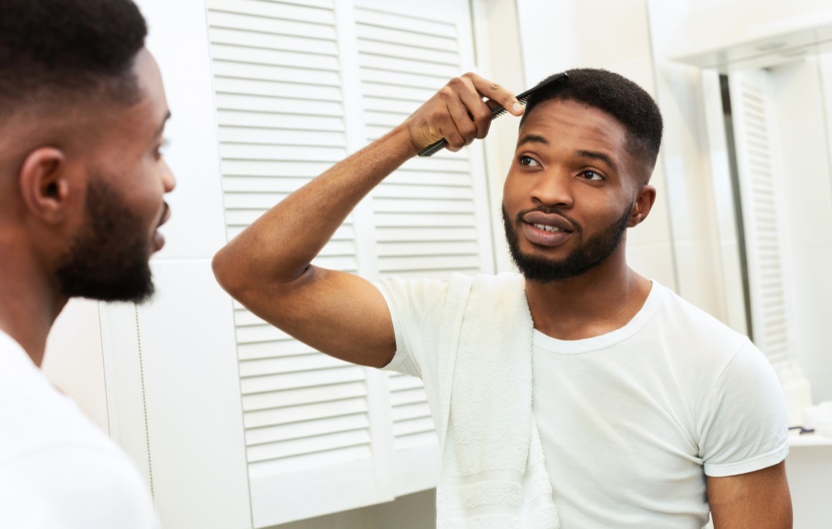 Man combing his hair in the mirror