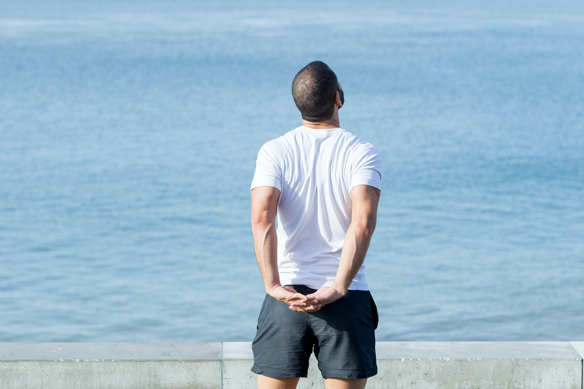 Strong Man Stretching Arms Behind Back at Sea