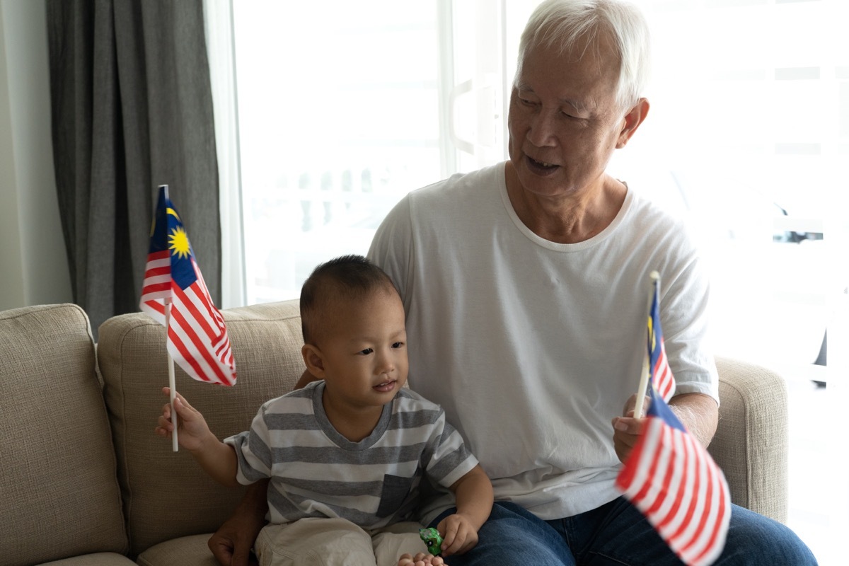 Grandfather with grandson holding Malaysian flags