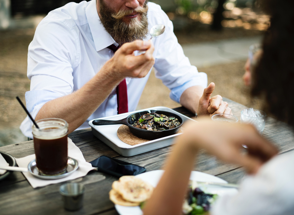 Man eating from cast iron skillet at table