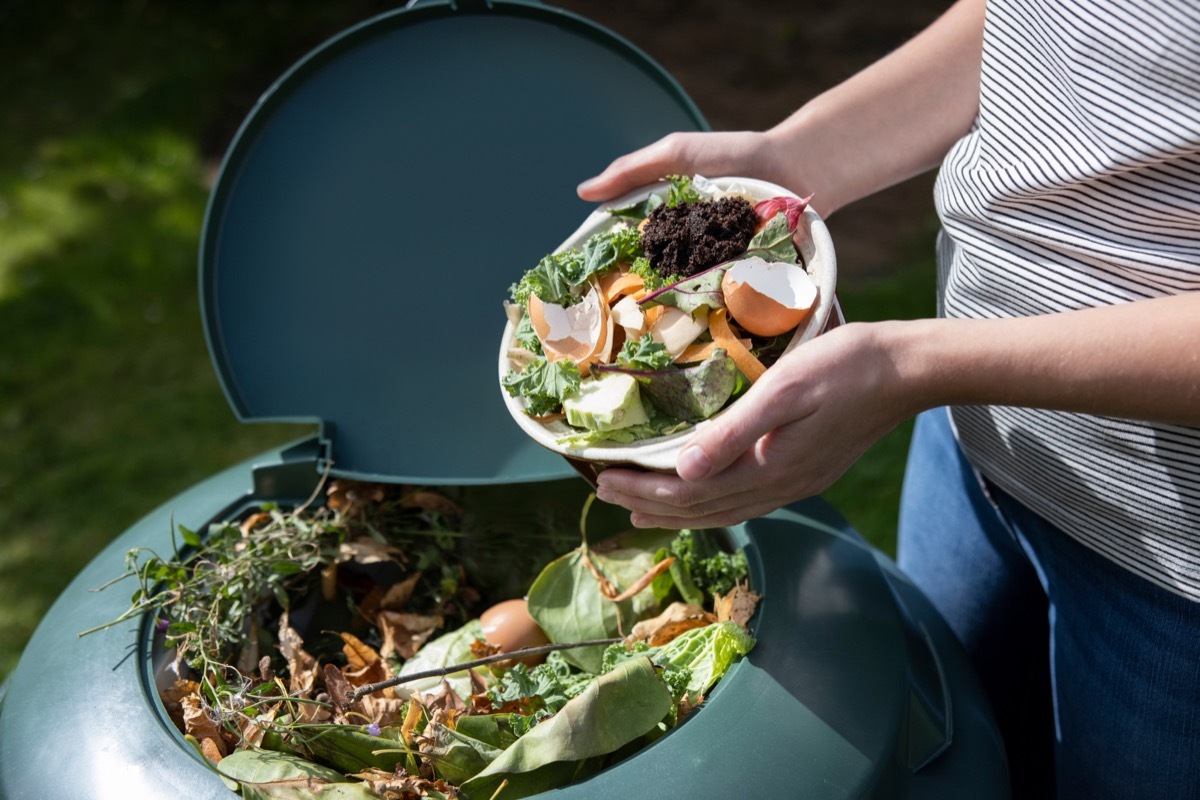 woman pouring compost into composter with egg shells on top