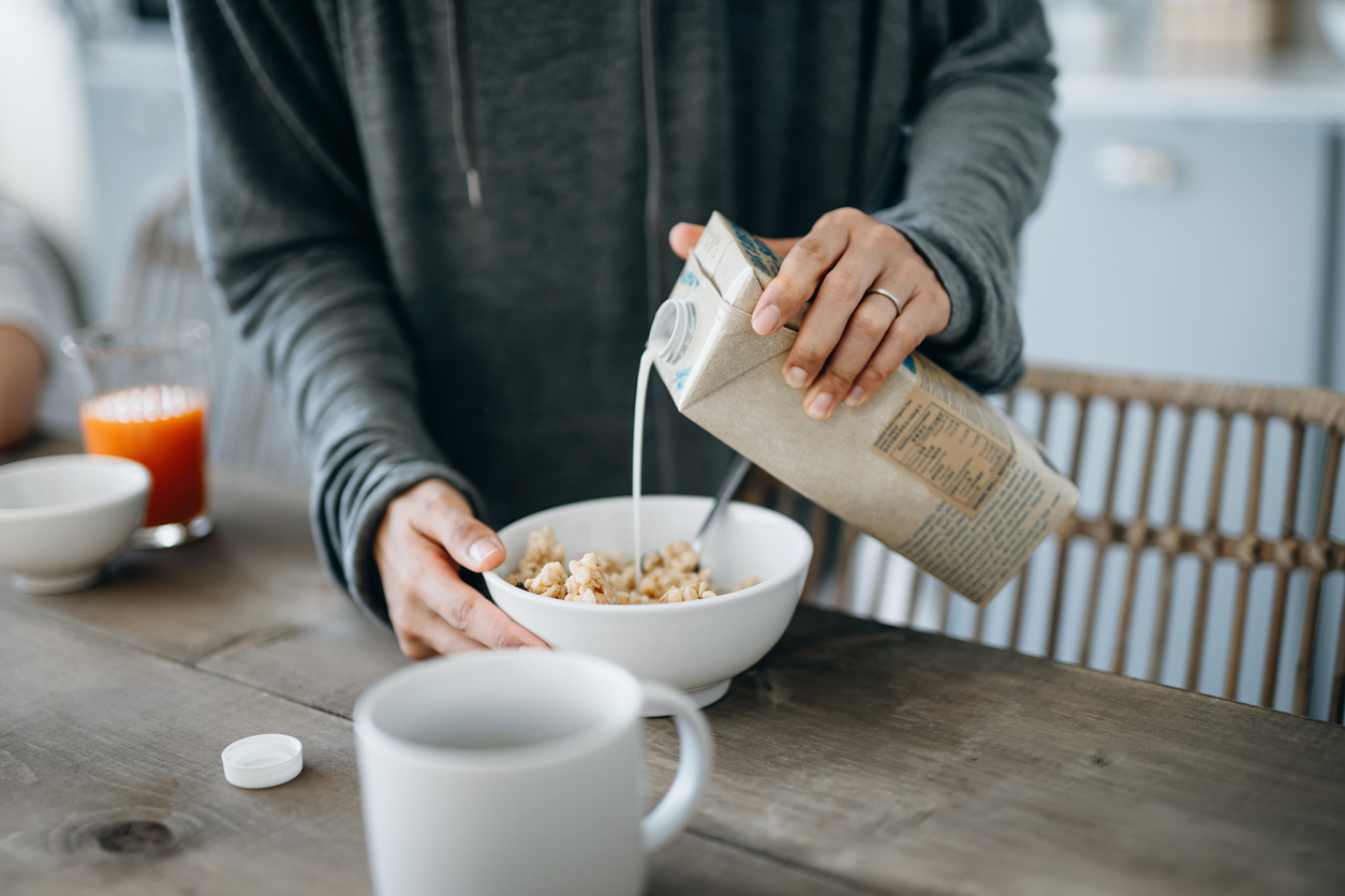 Person pouring milk into a bowl full of cereal. 