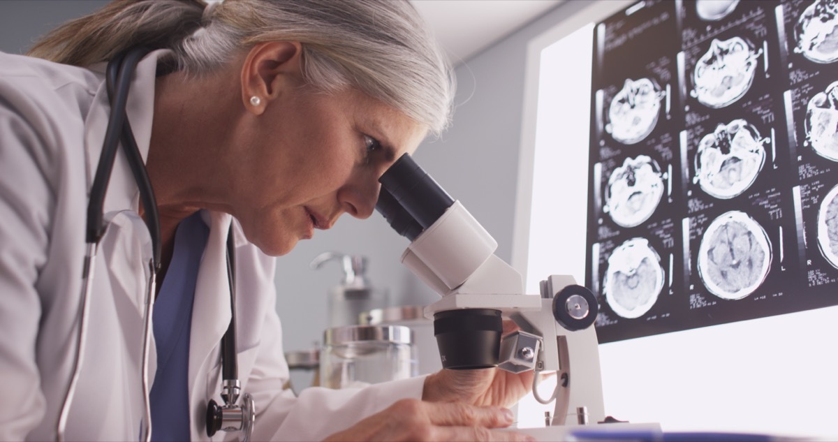 Middle aged neurologist female researching with microscope