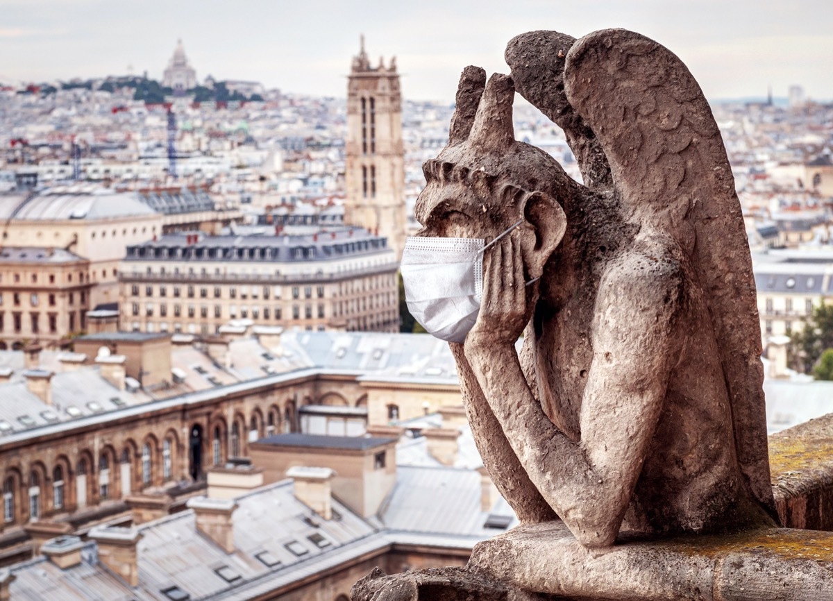 COVID-19 coronavirus in France, medical mask on gargoyle of Notre Dame in Paris