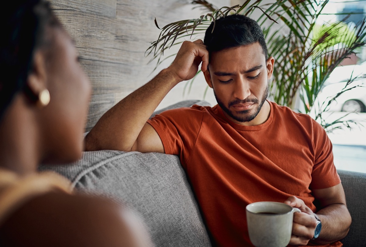 Shot of a handsome young man sitting with his girlfriend in the living room at home and looking upset