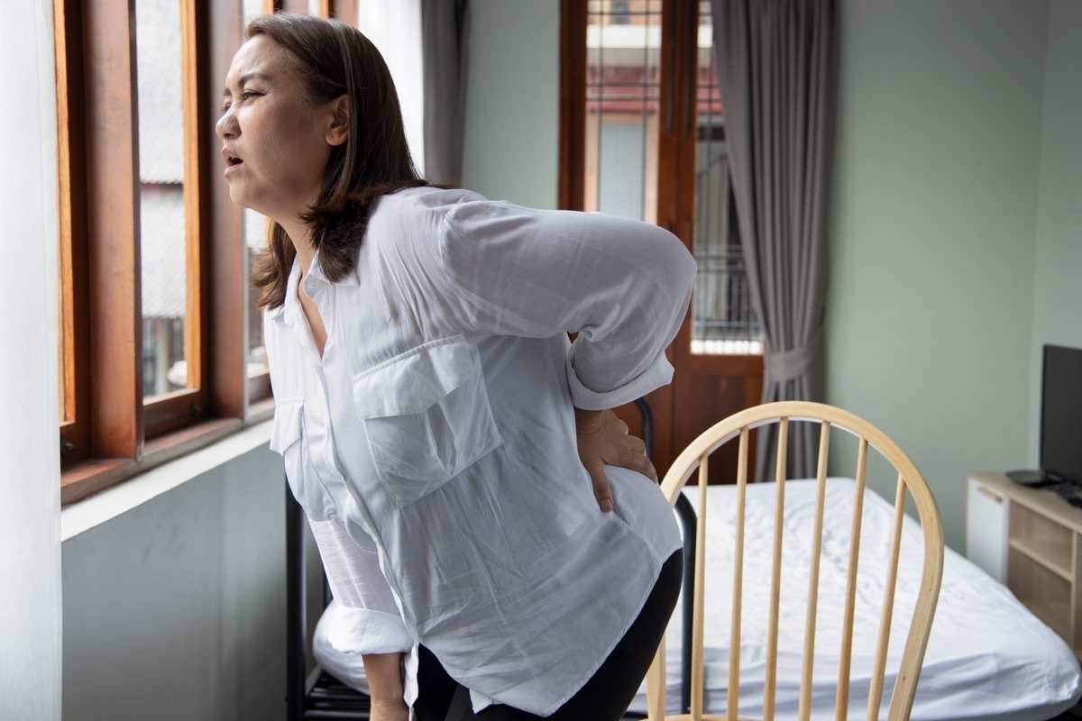 Woman with herniated disk and back pain trying to get out of chair