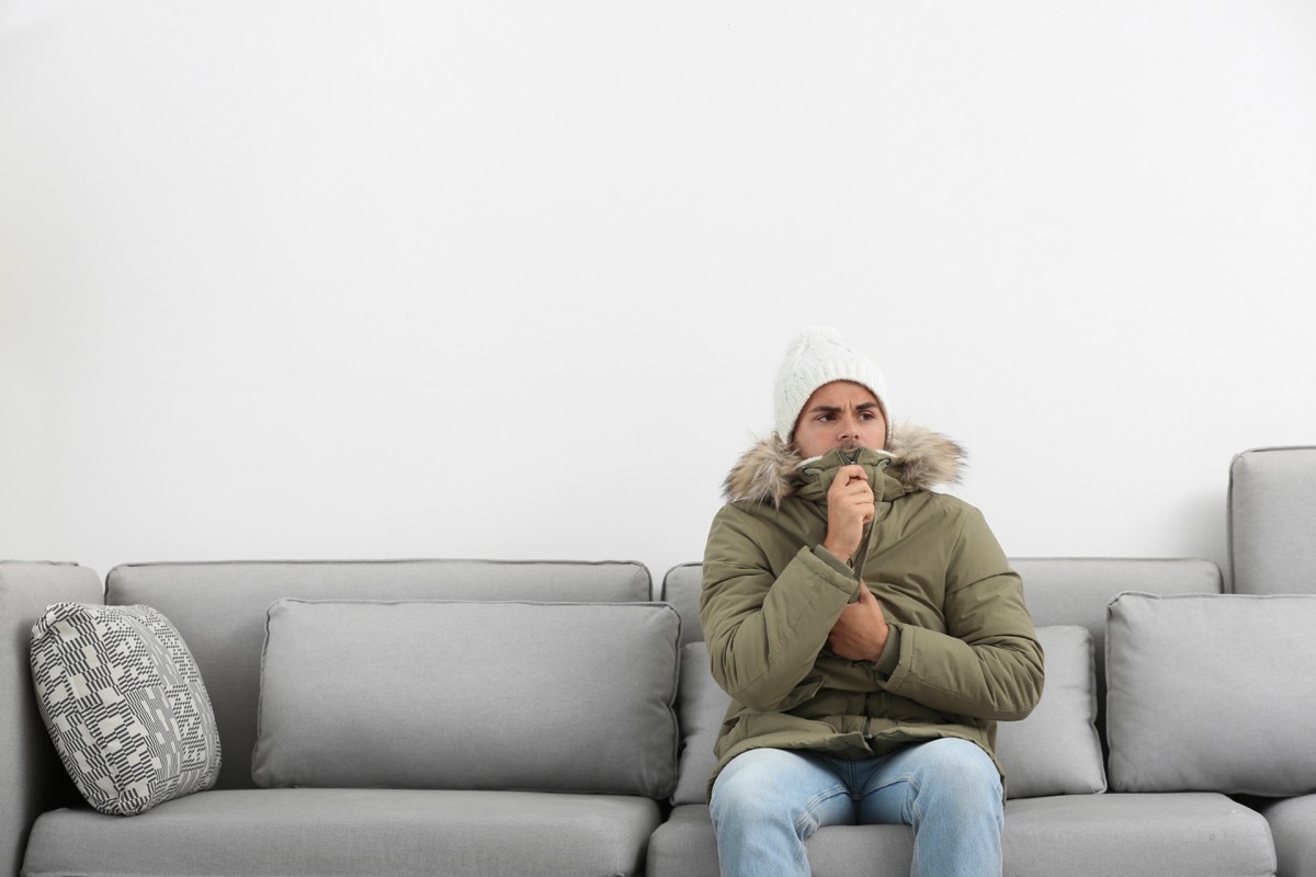 Man freezing in his living room wearing a jacket