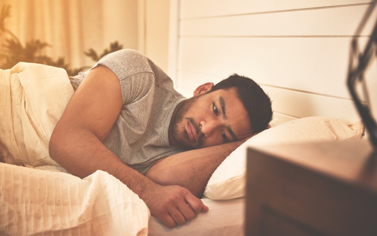 Sad-looking man laying awake in bed