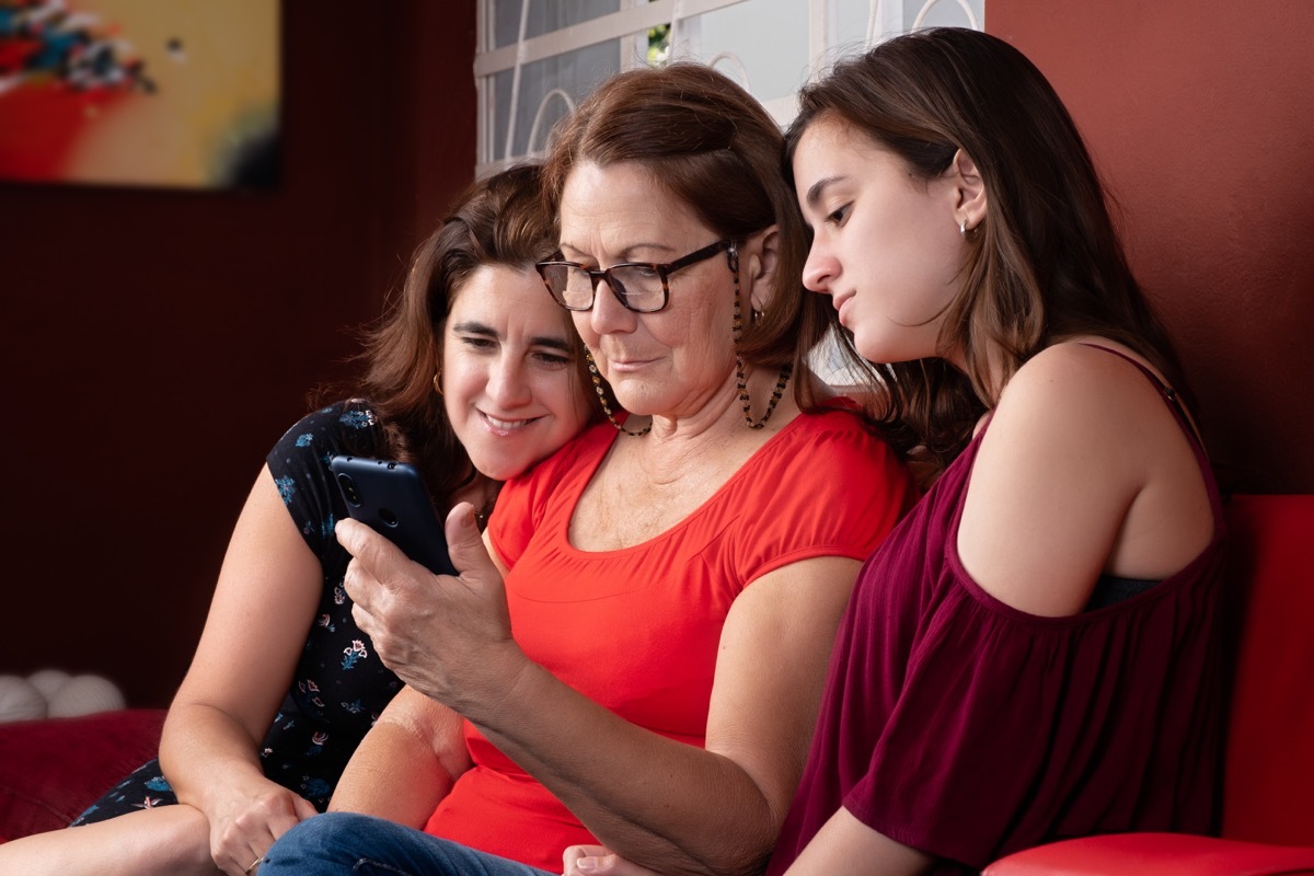 hispanic grandma and daughter and granddaughter looking at phone