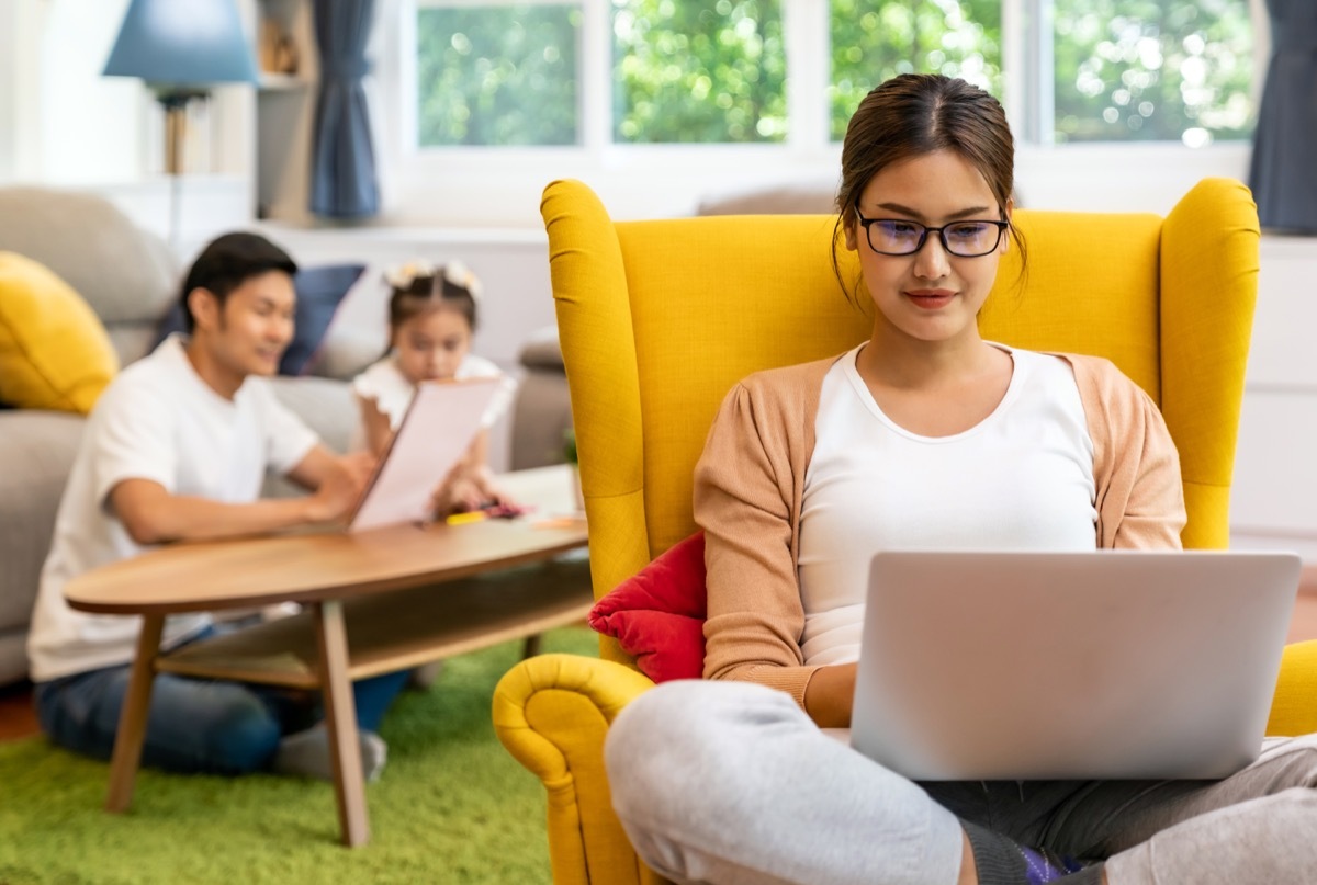 working mom work from home in living room with background of father and daughter reading tale story book