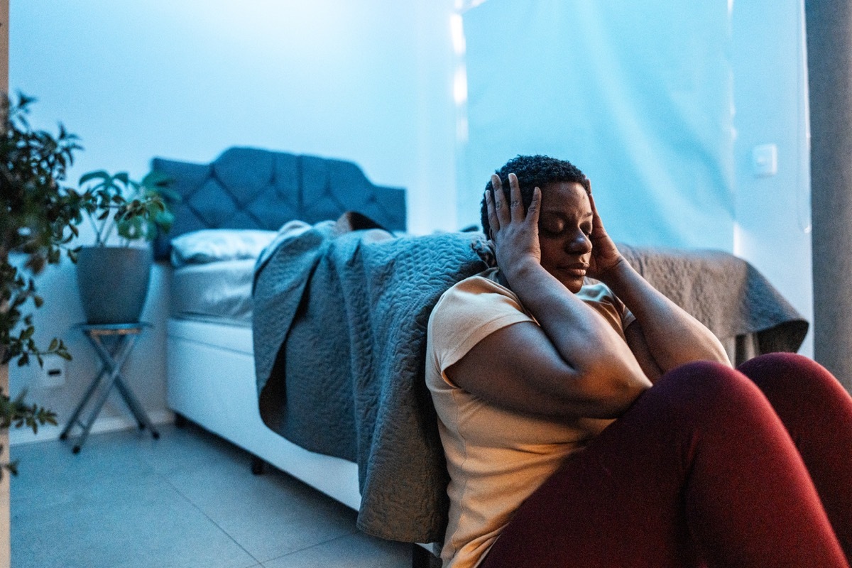 Mature woman feeling bad sitting on the floor in the bedroom at home