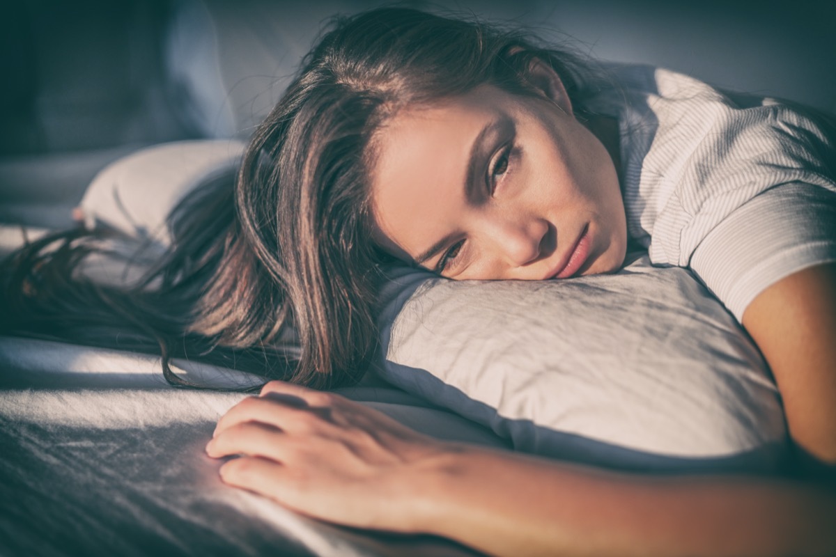 Tired woman lying in bed can't sleep late at night with insomnia