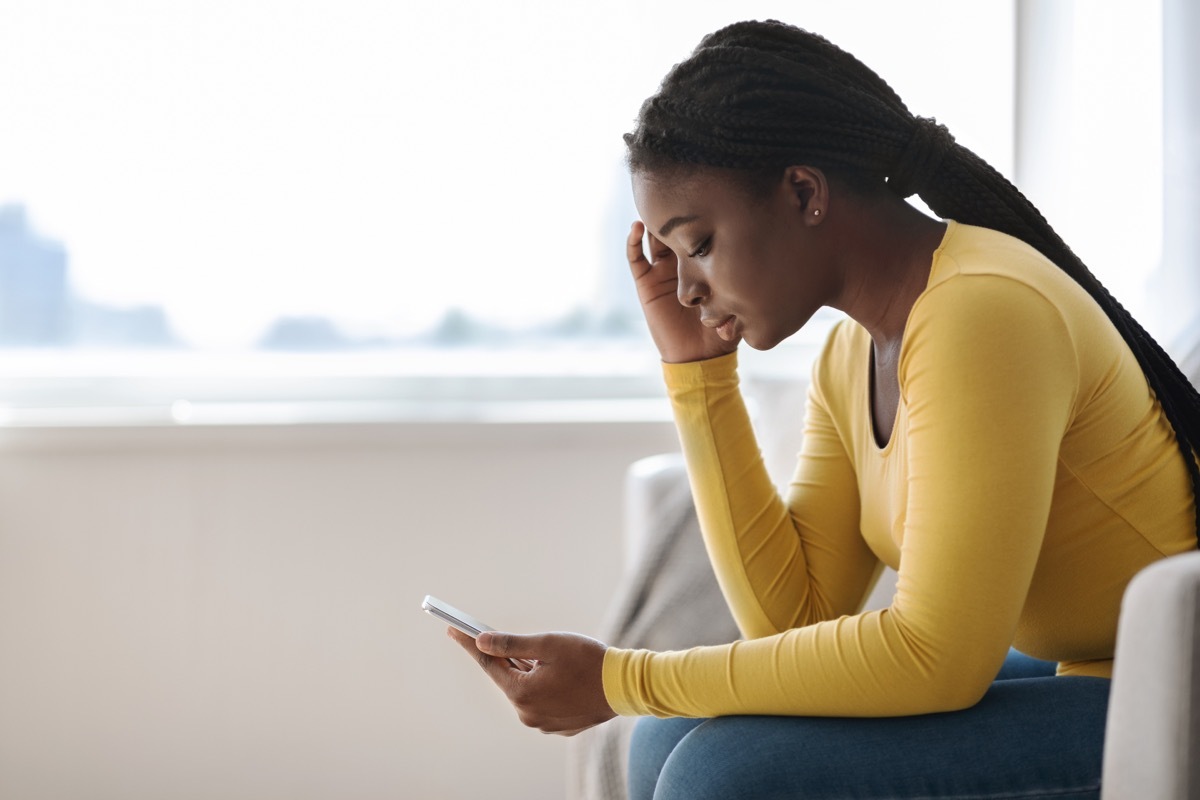 Woman upset looking down at her phone. 