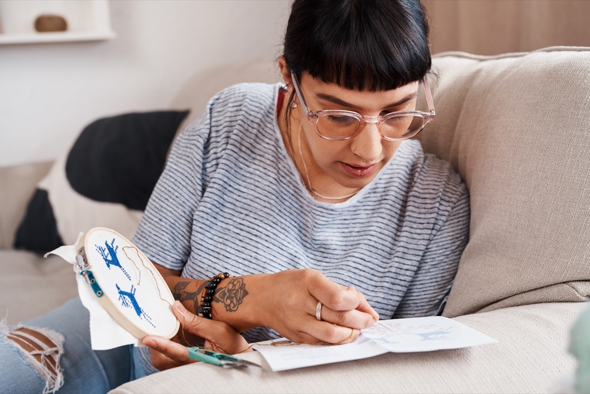 Shot of a beautiful young woman doing embroidery at home