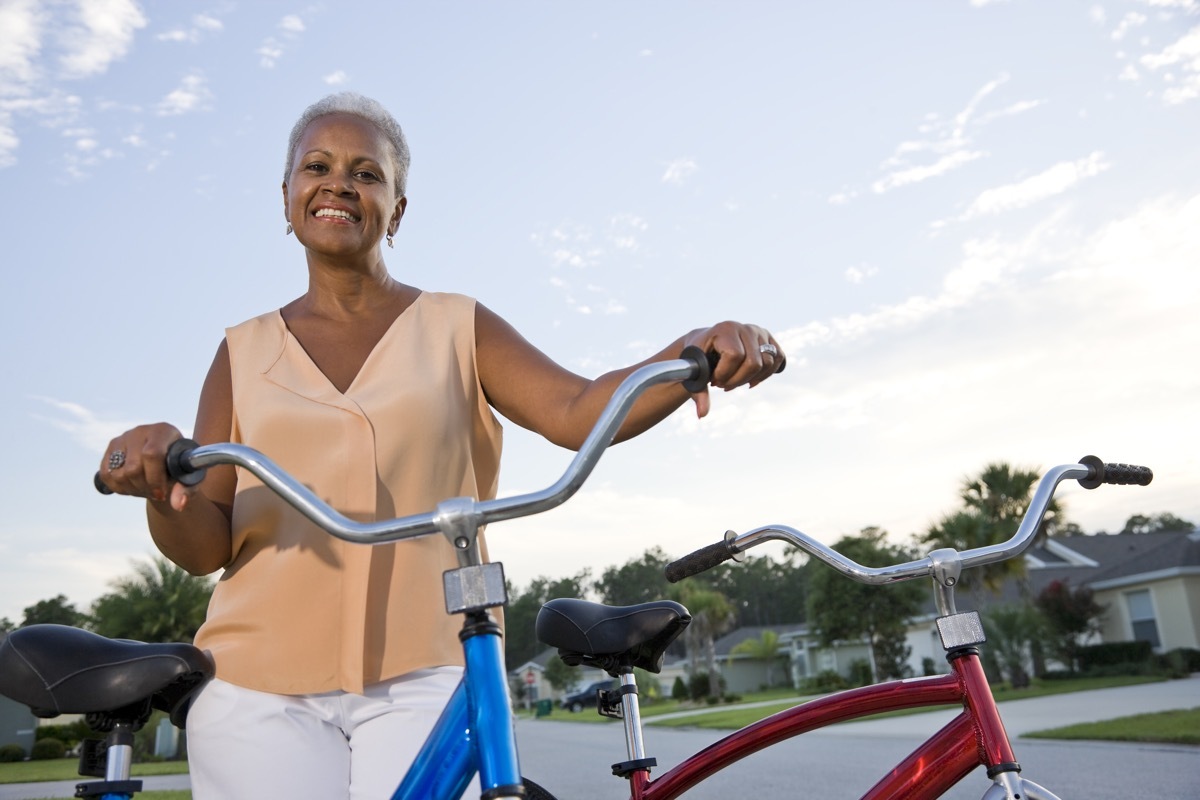 senior woman in pale orange top with bike