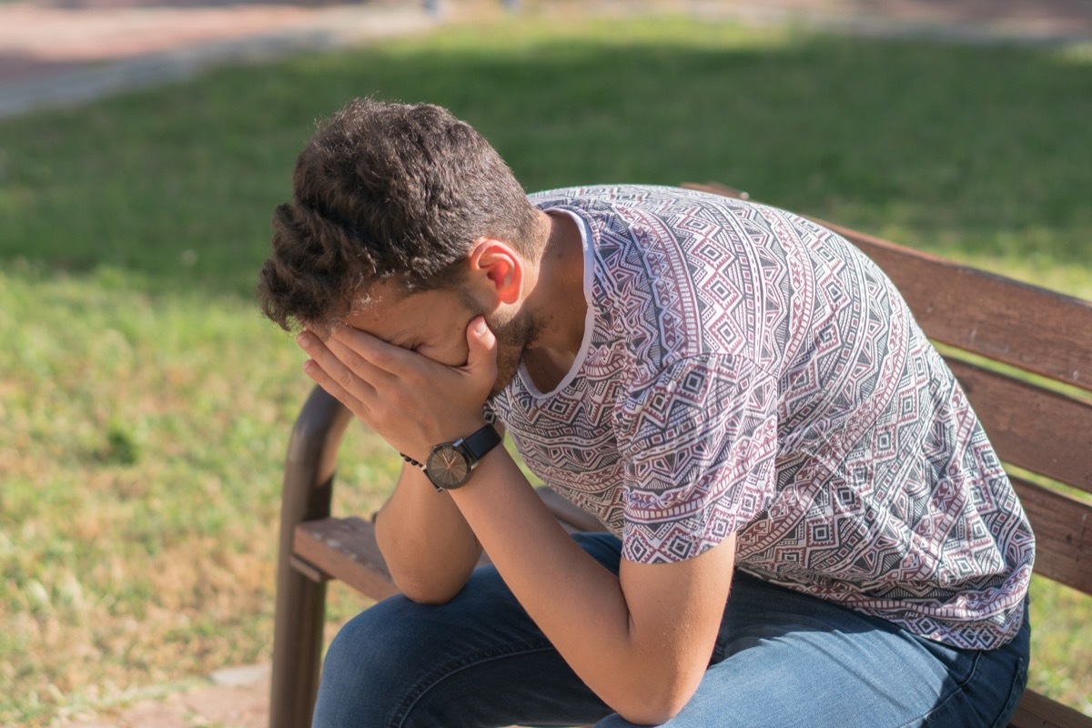 Sad young man on the park bench