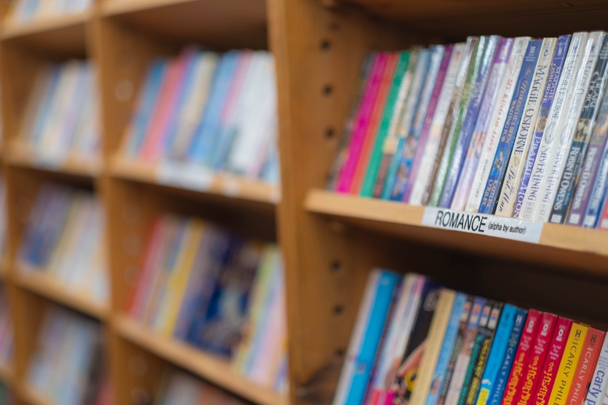 Shelf with a row of romance books. Blurry background. Colorful books in a row at a store.