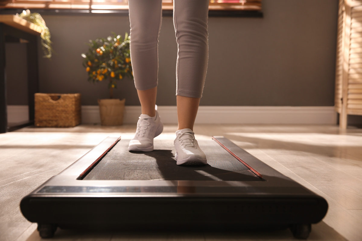 Sporty woman training on walking treadmill at home, closeup