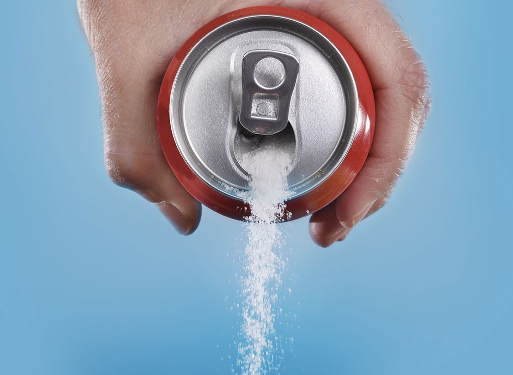 hand pouring sugar out of a soda can