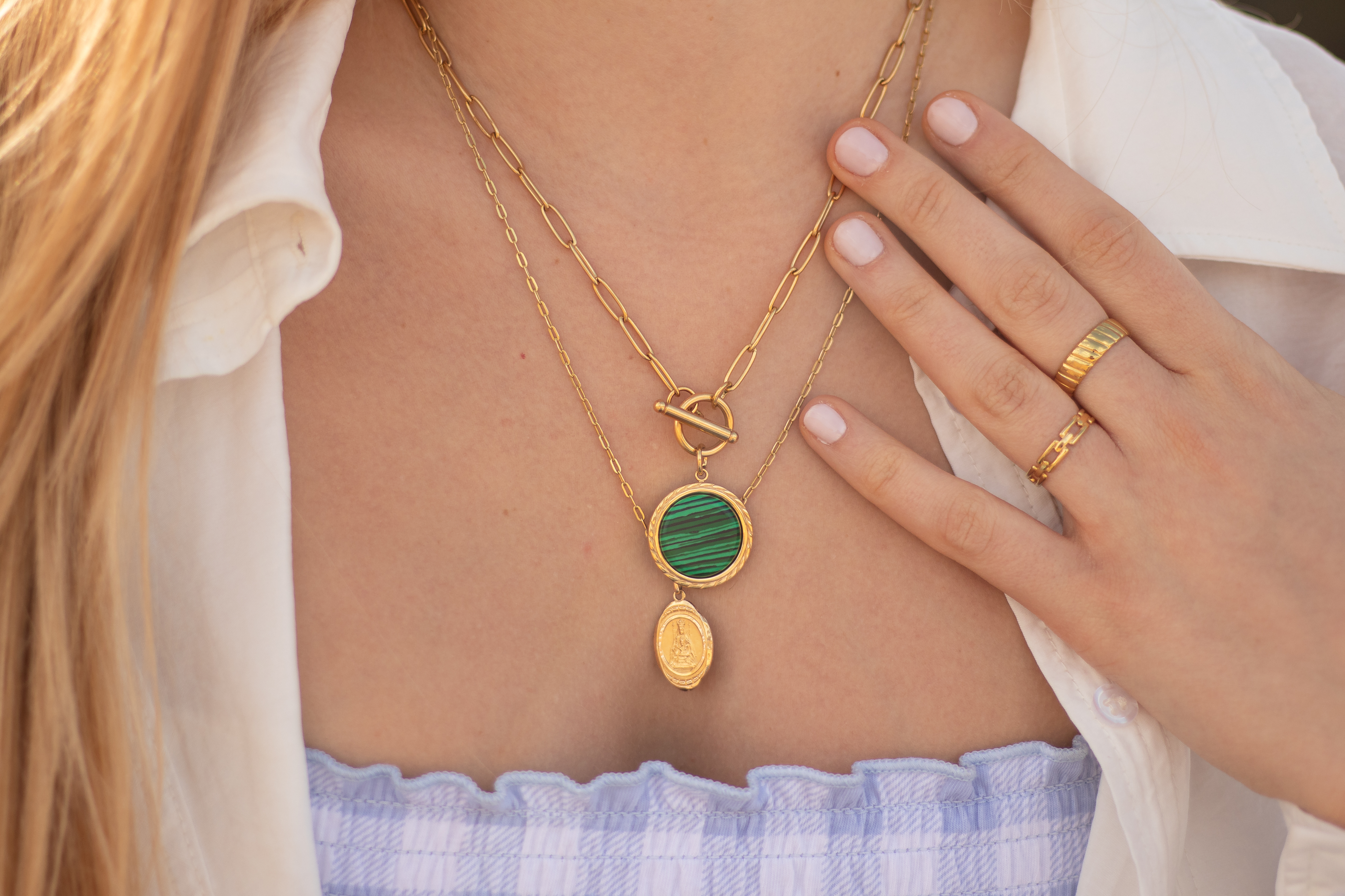 Young woman wearing golden jewelry. Golden necklace and golden rings.