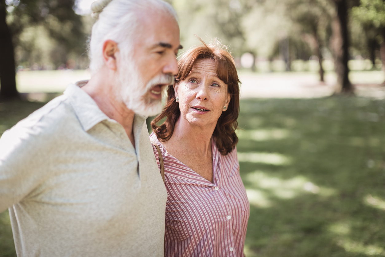 A senior couple walking together through a park