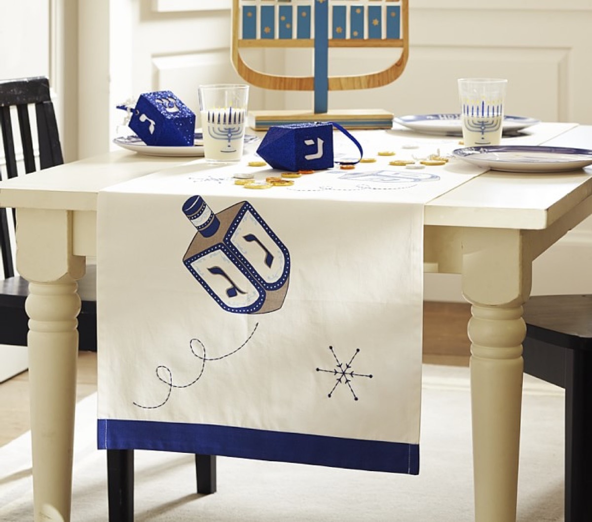 white table runner with dreidel on it and menorahs on the table, hanukkah decorations