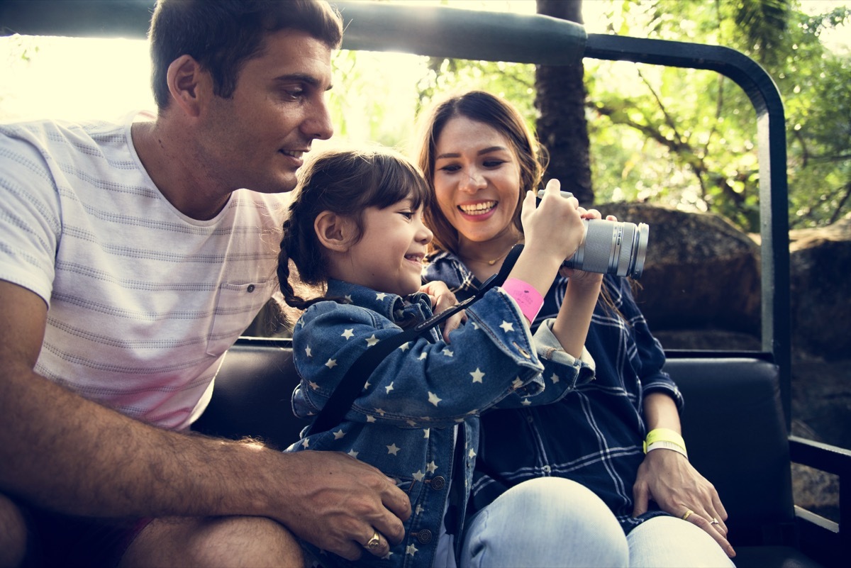 parents and daughter in golf cart taking photos on safari vacation