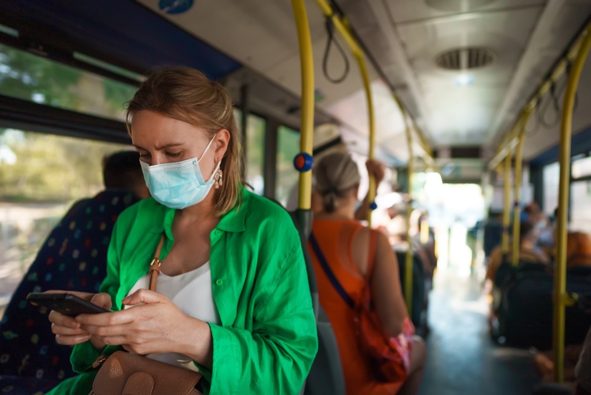 Woman in medical mask with mobile phone in the bus.