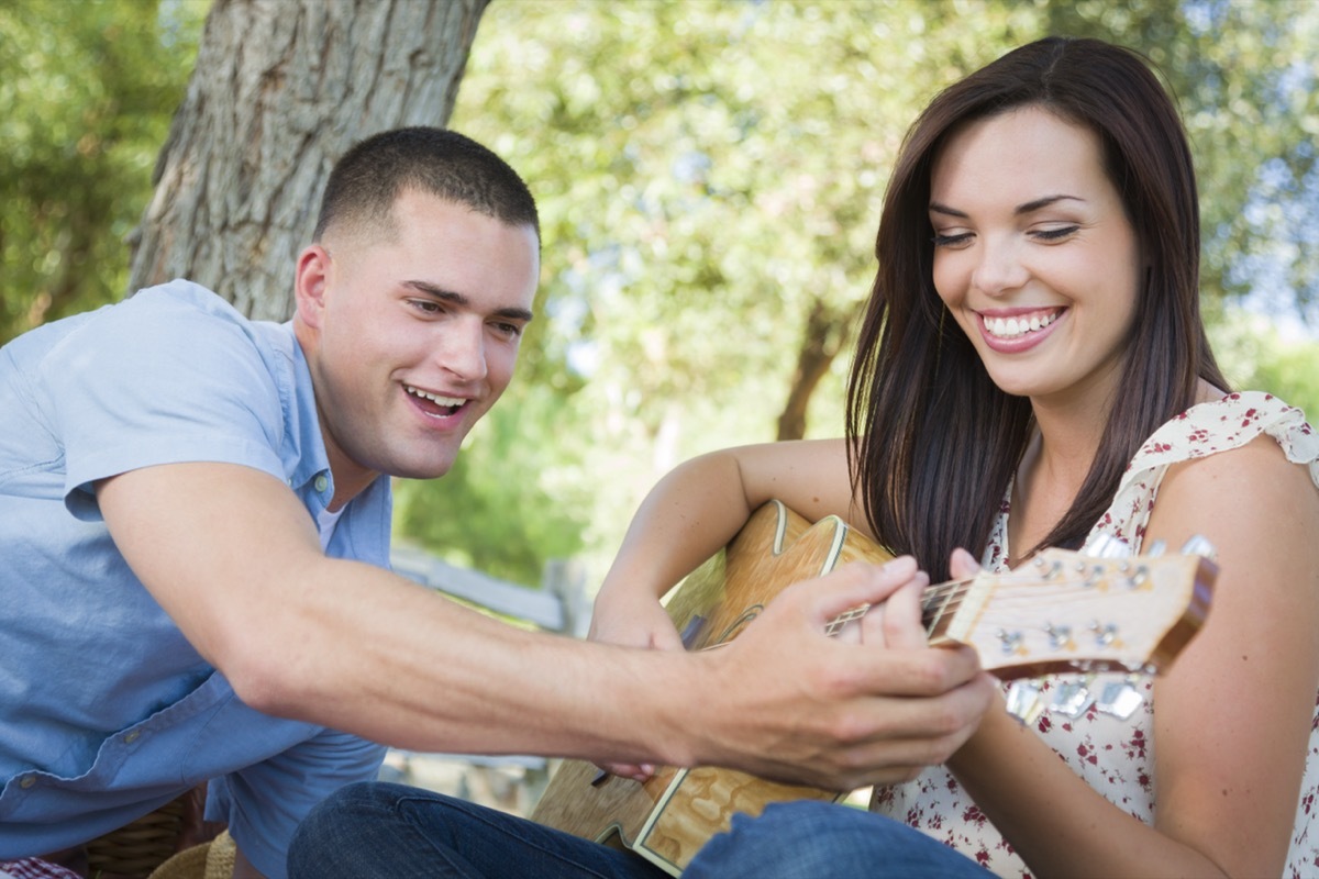 man teaching a woman how to play guitar